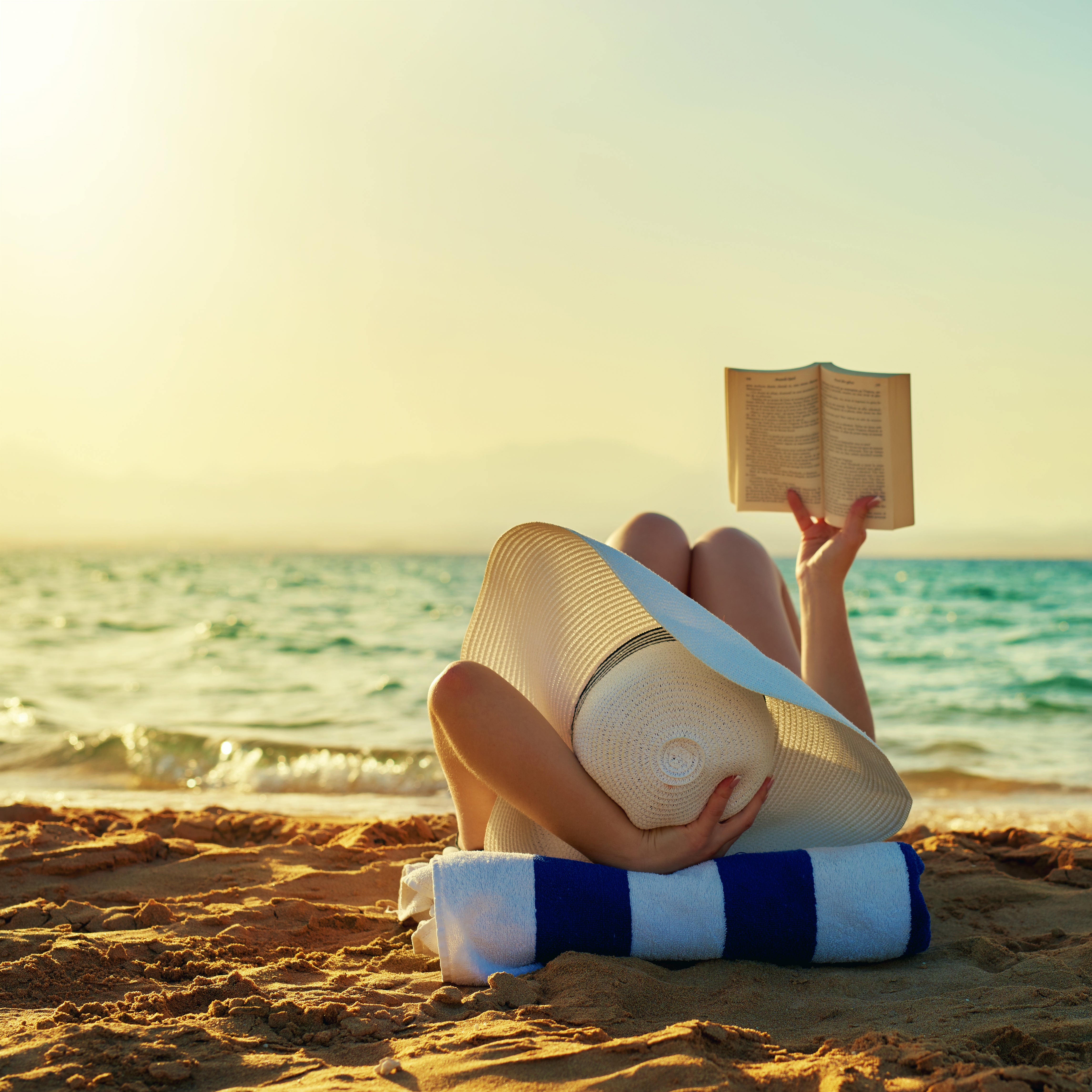 une-femme-profitant-de-la-plage-et-lisant-un-livre-au-bord-de-l'eau