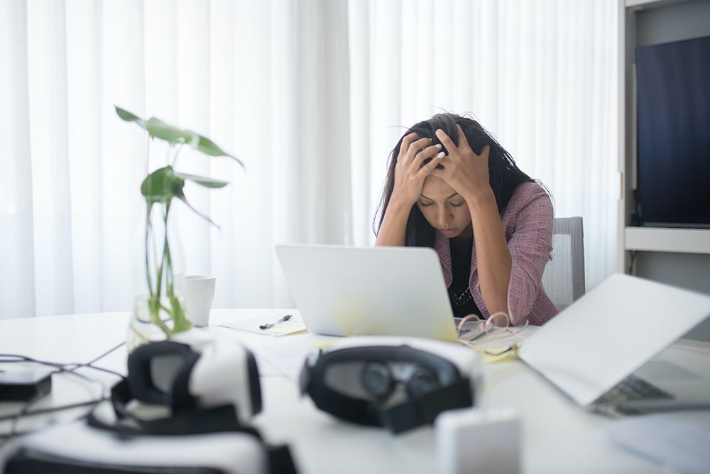 Women frustrated working on a computer holding her head