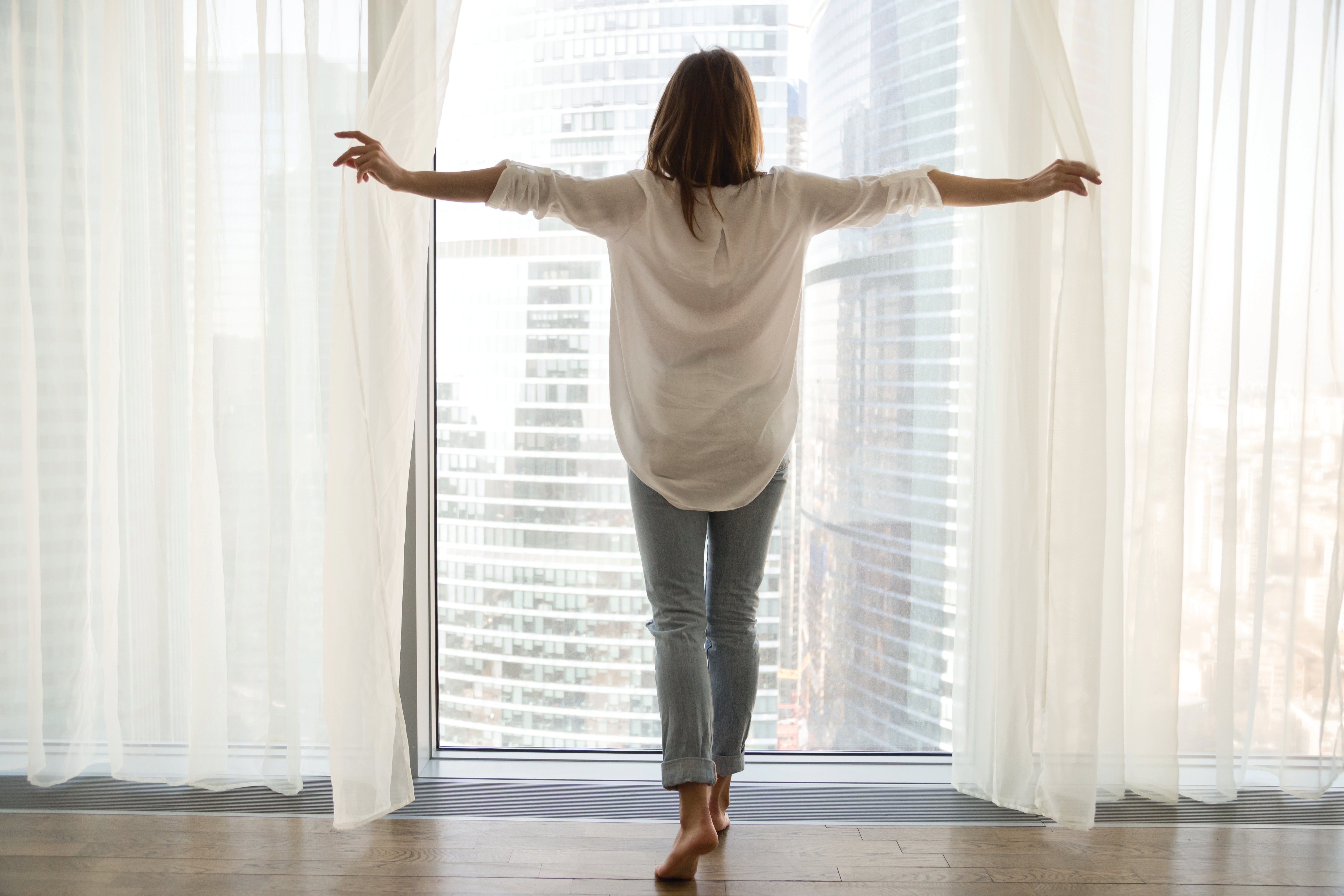 Women opening curtains and looking out window