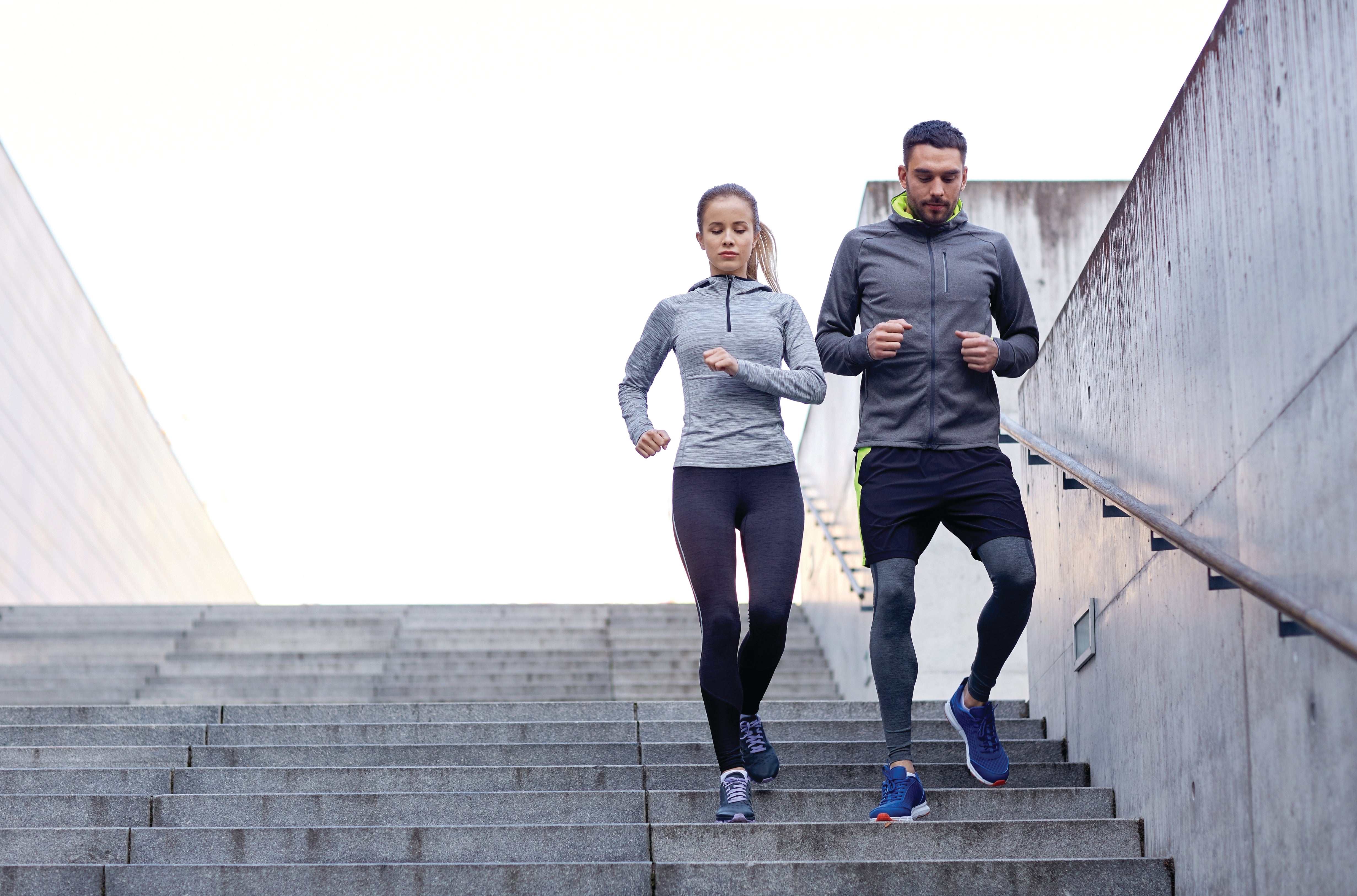 Homme et femme courant dans les escaliers, faisant de l'exercice à l'extérieur