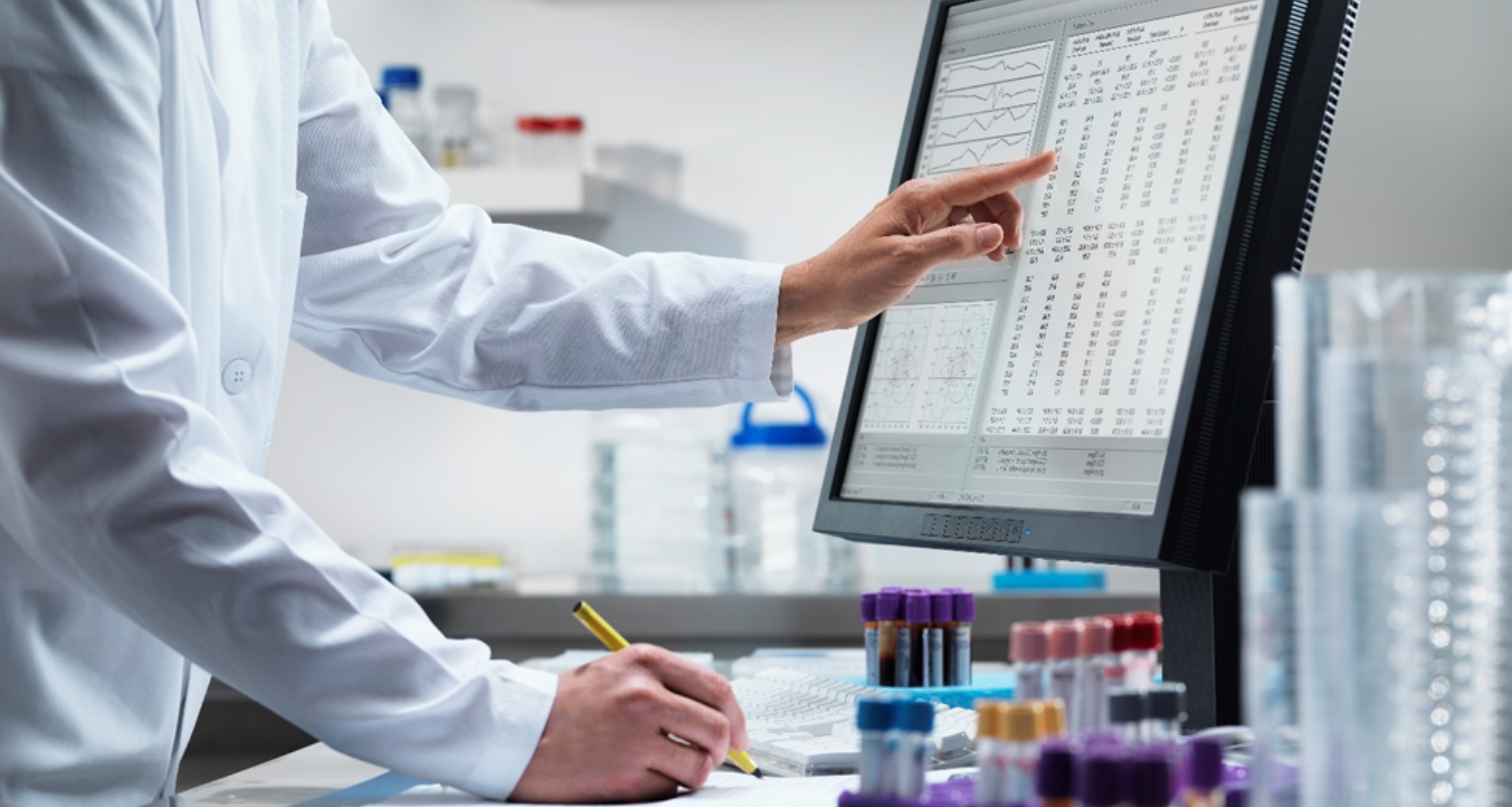 Doctor reviewing data on a computer screen and taking notes