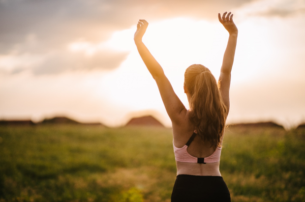 Women stretching outside looking at a sunrise.