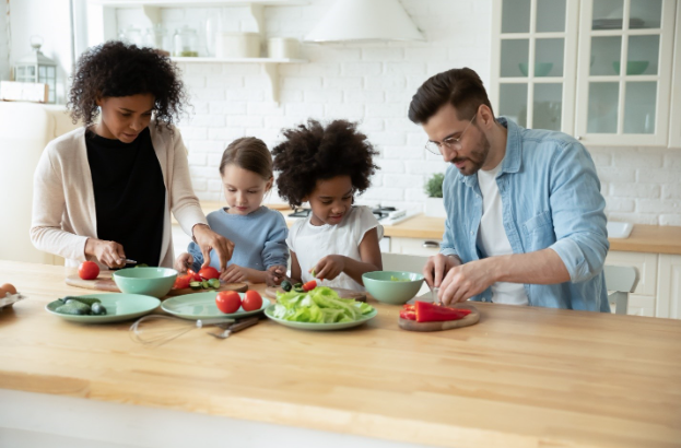 A husband and wife preparing a healthy lunch with their kids in the kitchen.