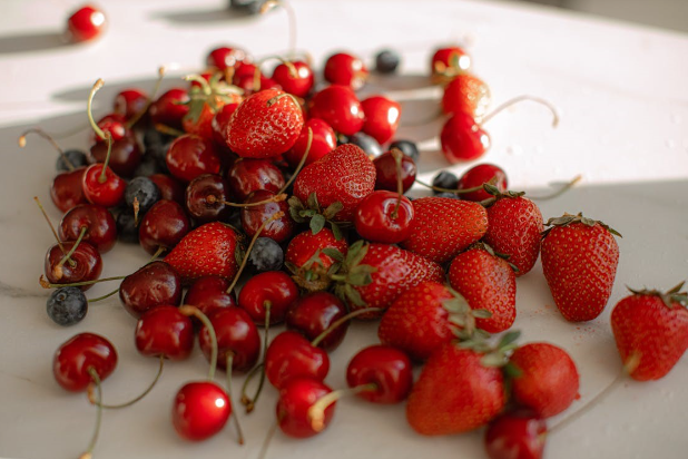 Fresh strawberries, cherries and blueberries on a kitchen counter.