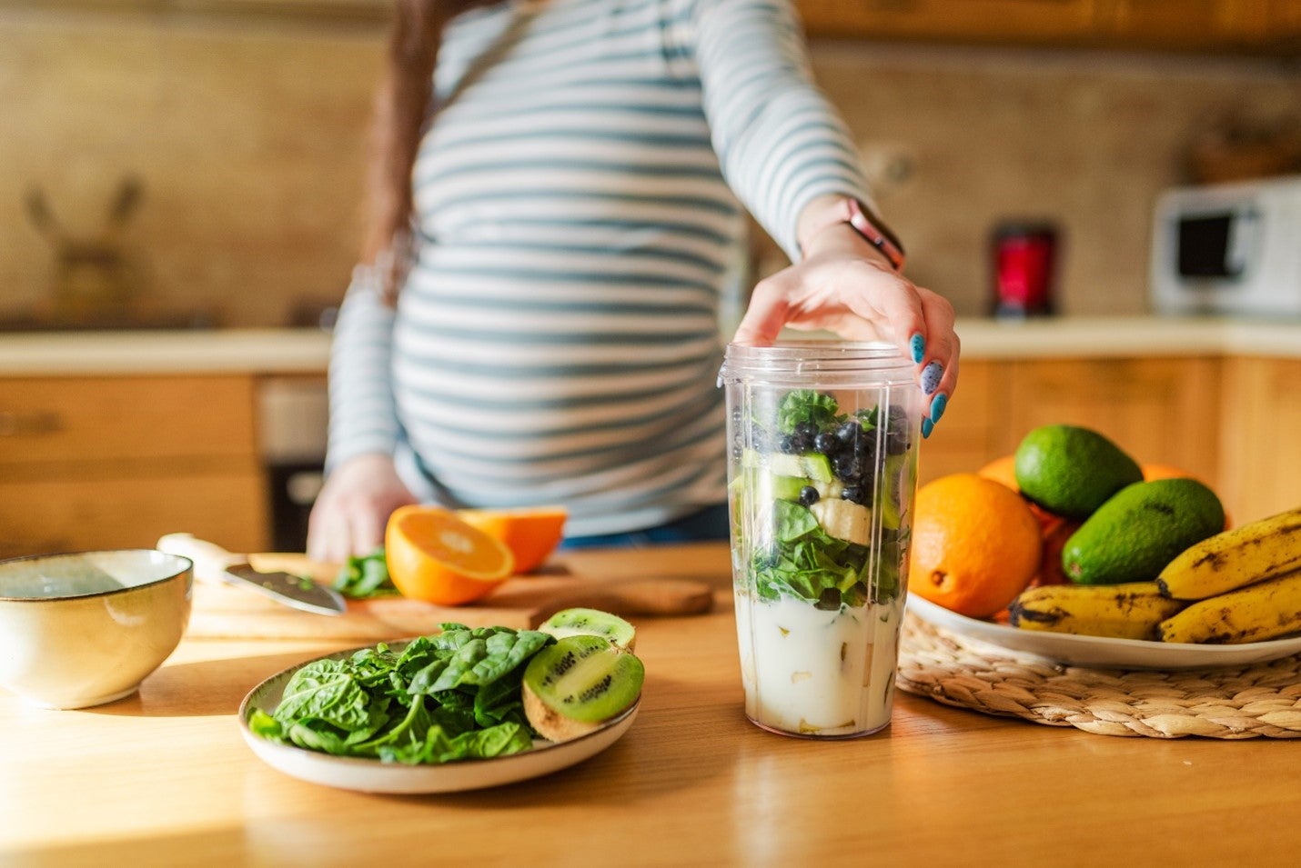 Une femme enceinte préparant un smoothie et un déjeuner sains