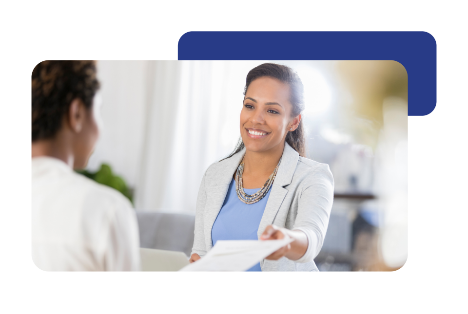 Smiling women is handing paperwork to a colleague. 